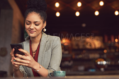 Buy stock photo Cropped shot of a young businesswoman texting on a cellphone in a cafe