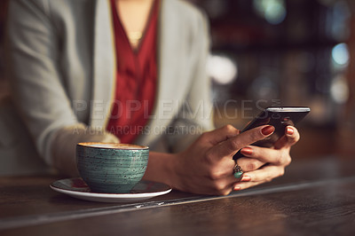 Buy stock photo Cropped shot of an unidentifiable woman texting on a cellphone in a cafe