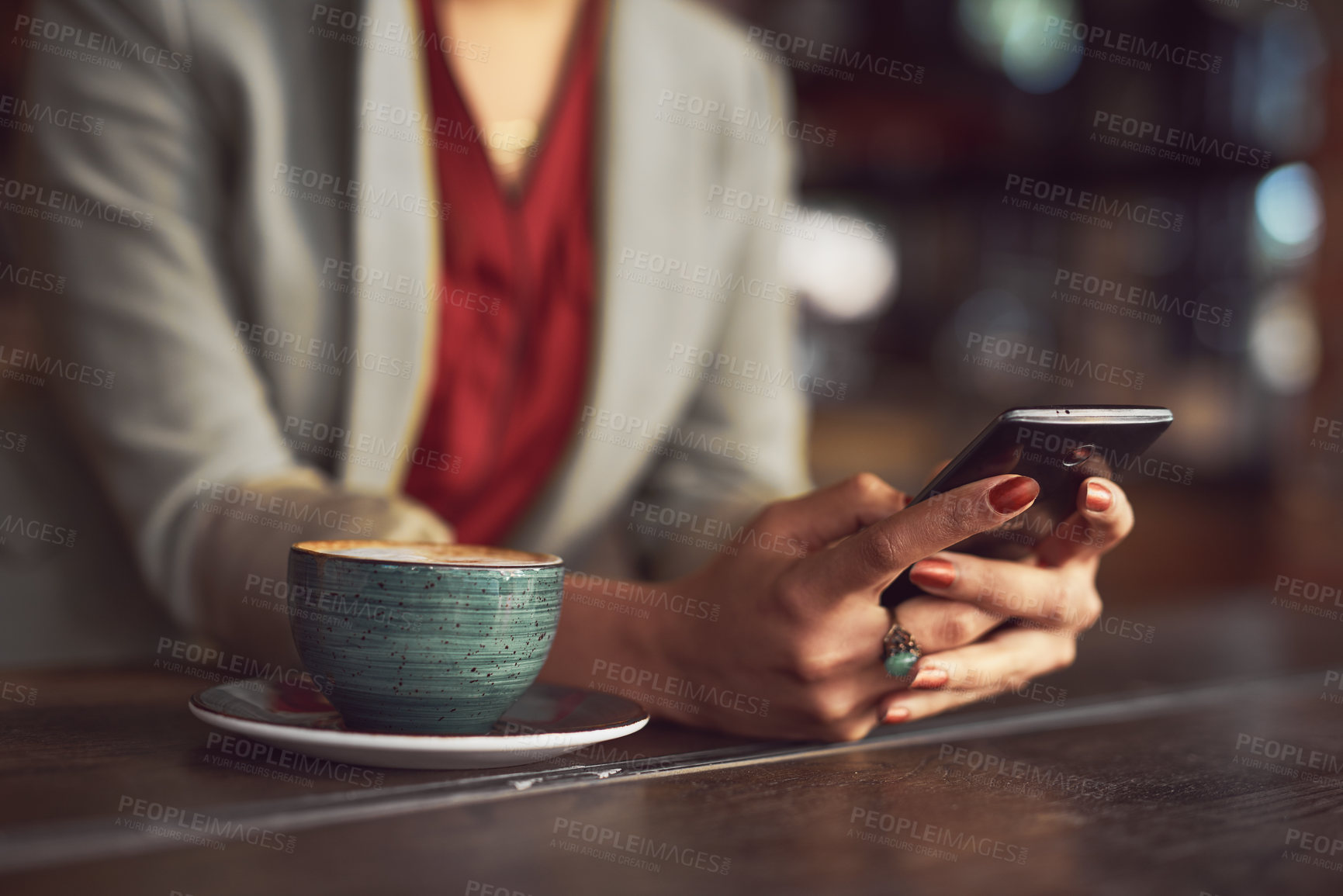 Buy stock photo Cropped shot of an unidentifiable woman texting on a cellphone in a cafe