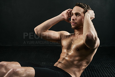 Buy stock photo Studio shot of a shirtless young man doing situps against a dark background