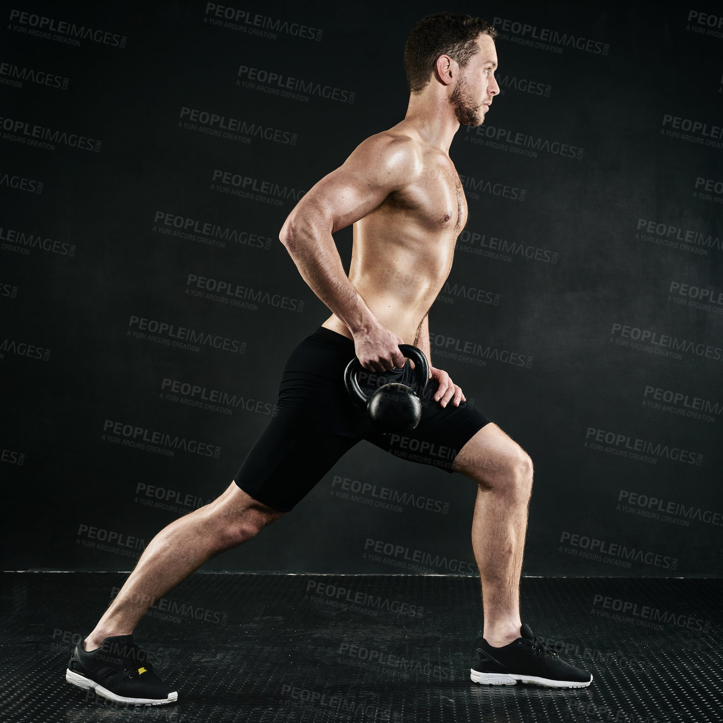 Buy stock photo Studio shot of a shirtless young man working out with a kettle bell against a dark background