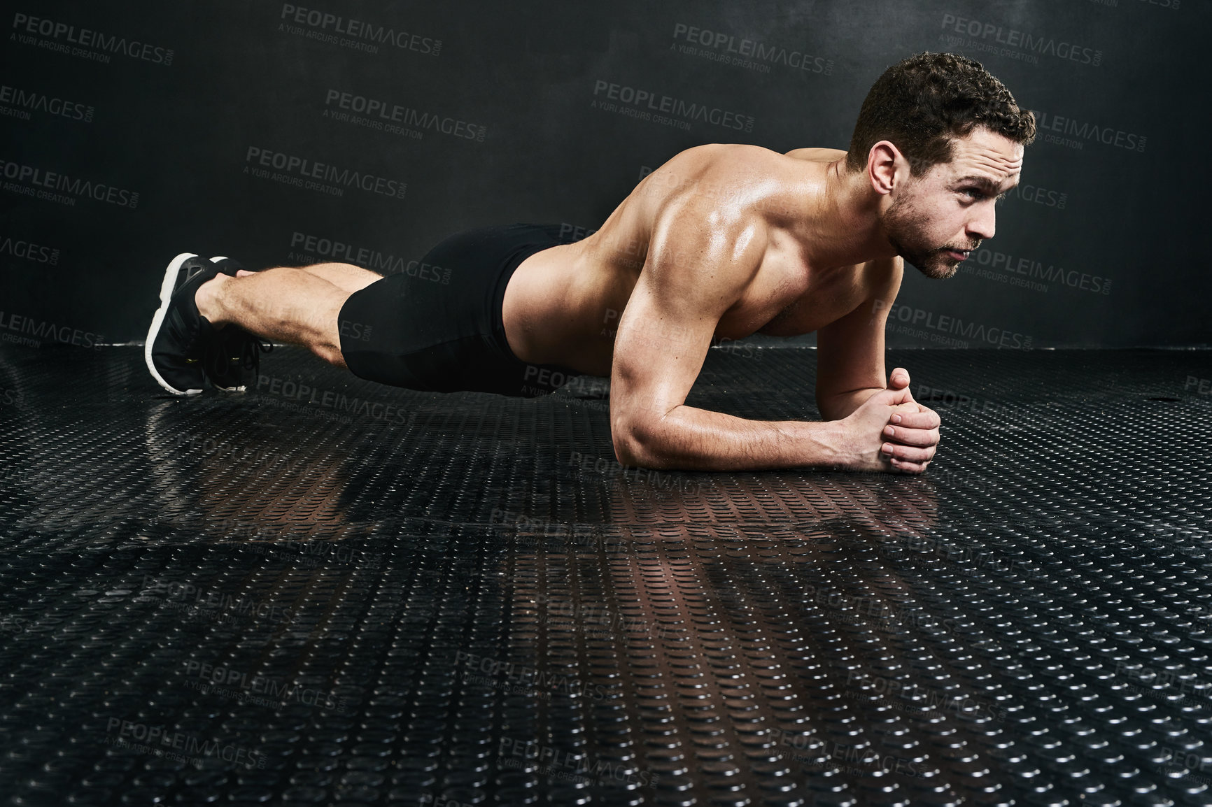 Buy stock photo Studio shot of a shirtless young man planking against a dark background