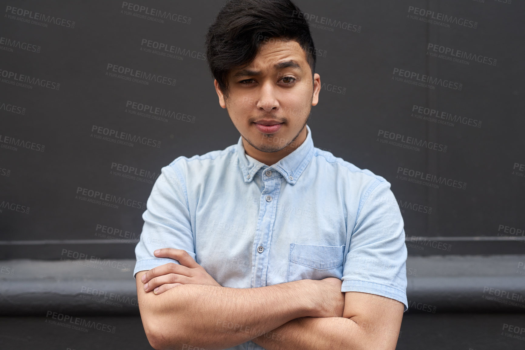 Buy stock photo Portrait of a young man standing with his arms folded outside