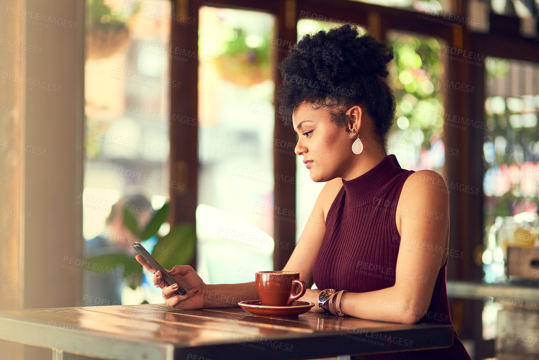 Buy stock photo Cropped shot of an attractive young woman texting on her cellphone in a cafe