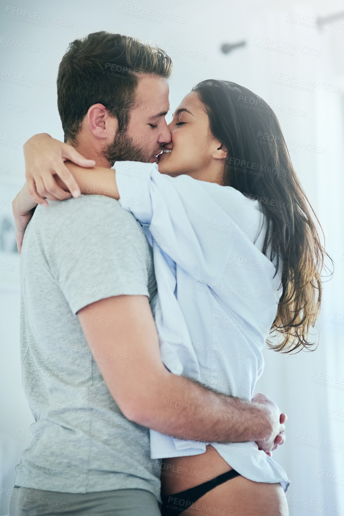 Buy stock photo Love, affection and happy couple in bedroom with kiss, romance and and morning bonding in apartment. Relationship, man and woman with intimate embrace, passion and relax with care on weekend in home