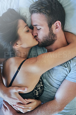 Buy stock photo Shot of a loving couple sharing a kiss in bed