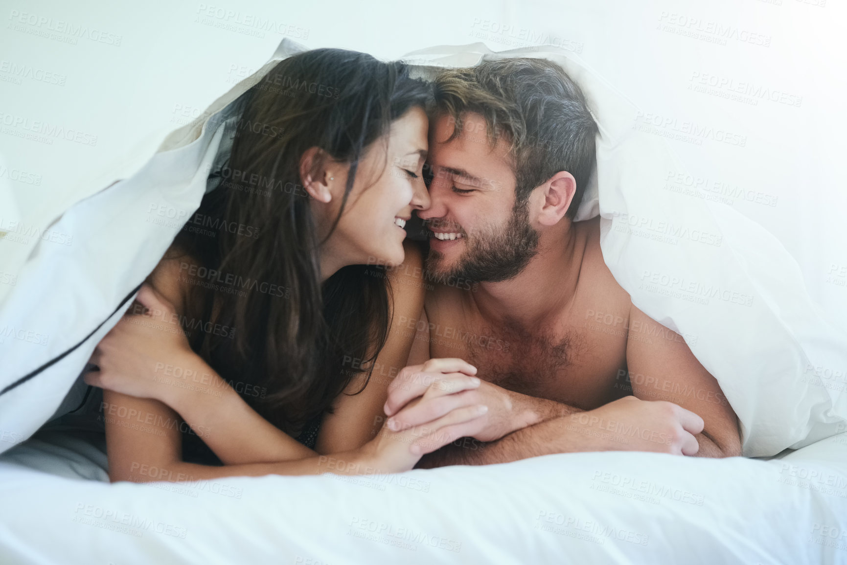 Buy stock photo Love, cover and couple in bed with kiss, romance and happy morning bonding in apartment. Relationship, man and woman in bedroom with intimate embrace, passion and relax with care on weekend in home