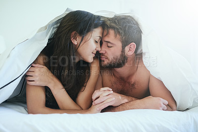 Buy stock photo Shot of a young couple having an intimate moment under the covers