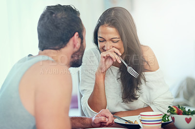 Buy stock photo Shot of a young man telling his girlfriend a joke while they enjoy breakfast at home