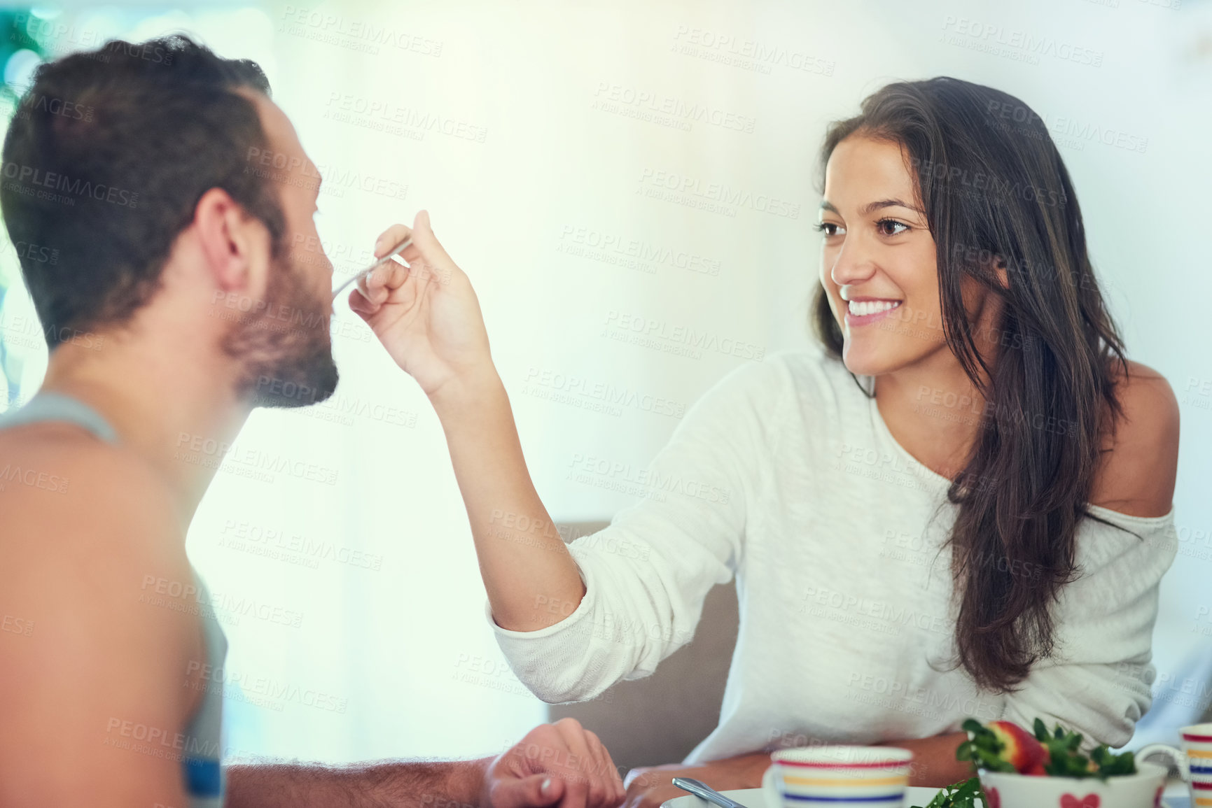 Buy stock photo Breakfast, home and couple feeding with food, happy and love together with marriage at table. Hungry, eating and woman with fruit and cooking in house with anniversary, romance and care with smile