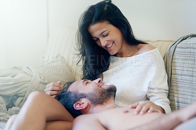 Buy stock photo Shot of a young couple enjoying a romantic moment on the sofa together in the morning