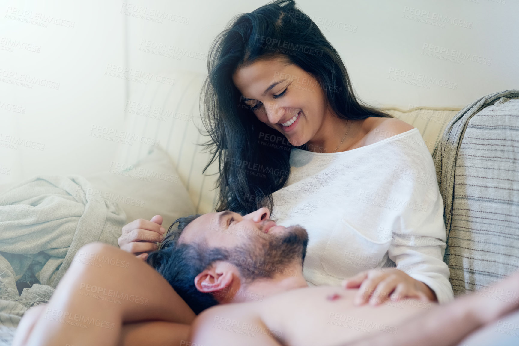 Buy stock photo Shot of a young couple enjoying a romantic moment on the sofa together in the morning