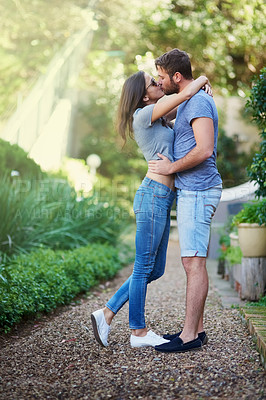 Buy stock photo Shot of a young kissing while enjoying a day together outside