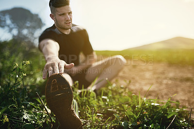 Buy stock photo Full length shot of a young man stretching outdoors before a run