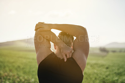 Buy stock photo Rearview shot of a young man stretching outdoors before a run