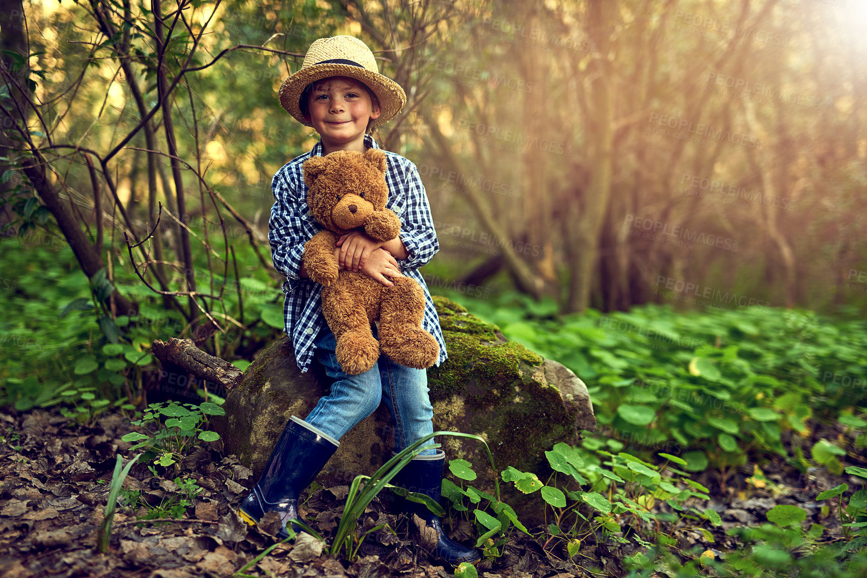 Buy stock photo Happy, young boy and teddy bear in wood for adventure with straw hat and rain boots for exploration in nature. Excited, male kid and stuffed animal in forest with trees for fun, relax and discovery 