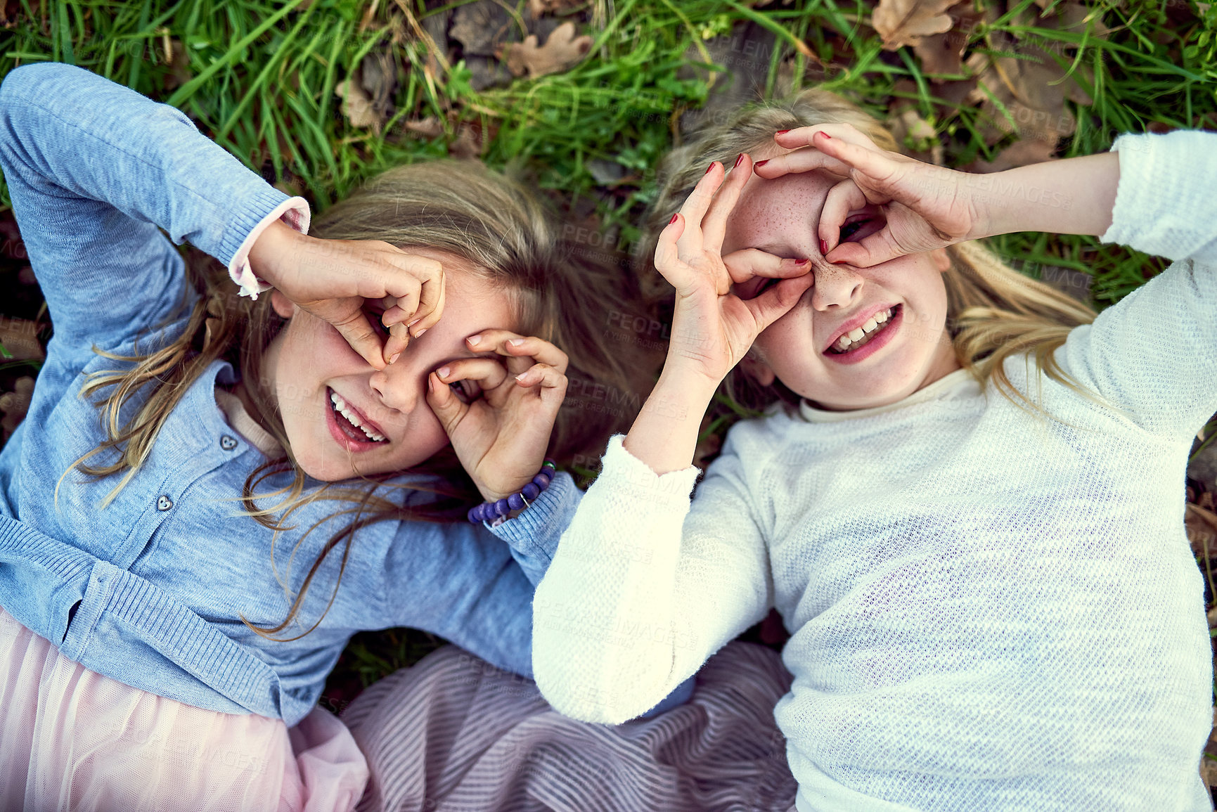 Buy stock photo Portrait of two little sisters lying on the grass outside
