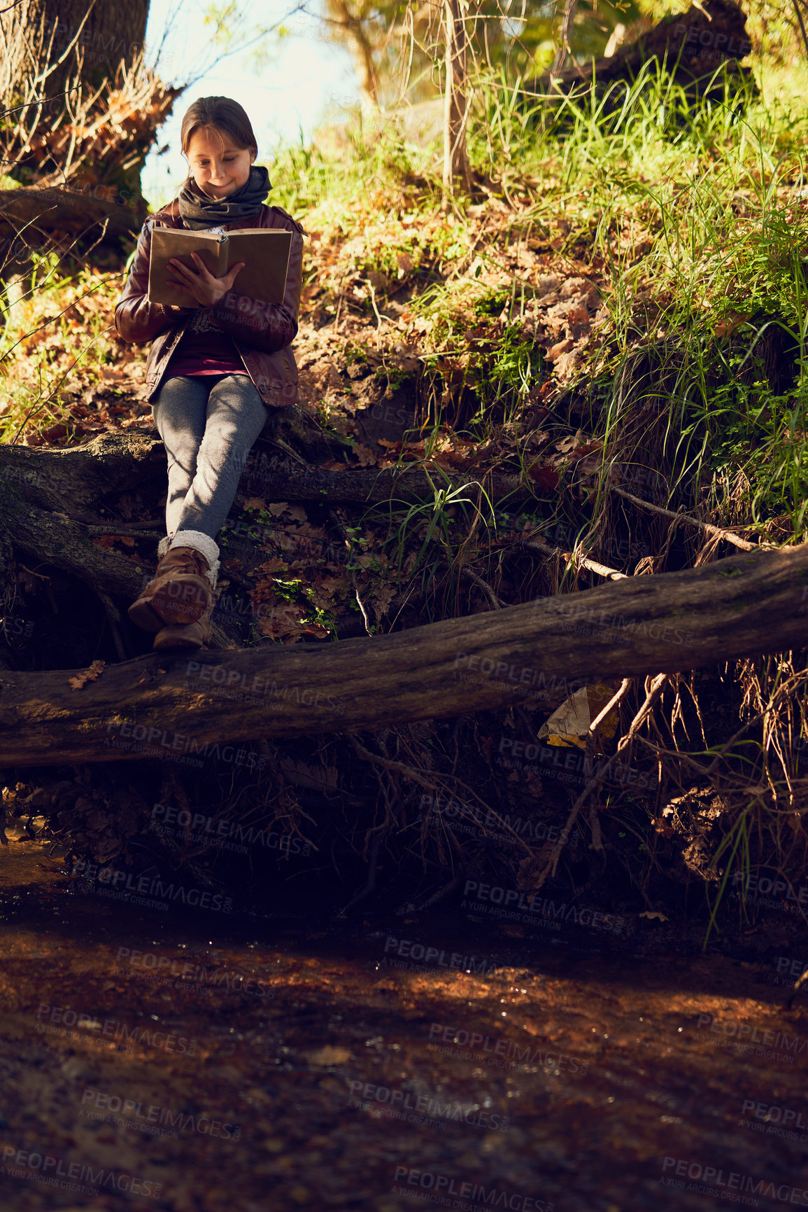 Buy stock photo Shot of a young girl reading a book outdoors