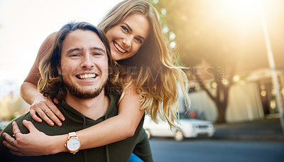 Buy stock photo Portrait of a happy young couple enjoying a piggyback ride in the city