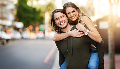 Buy stock photo Portrait of a happy young couple enjoying a piggyback ride in the city