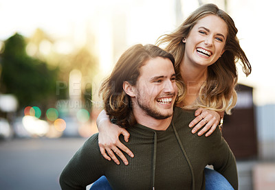 Buy stock photo Portrait of a happy young couple enjoying a piggyback ride in the city