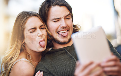 Buy stock photo Portrait of a young couple taking playful selfies together on their digital tablet