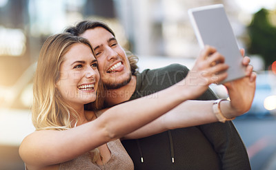 Buy stock photo Portrait of a happy young couple taking a selfie on their digital tablet