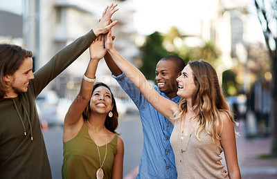 Buy stock photo Shot of a group of young friends giving each other a high five