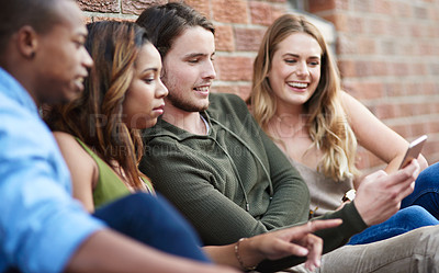 Buy stock photo Shot of a group of young friends using a mobile phone together