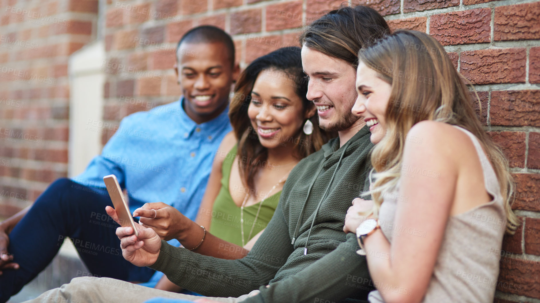 Buy stock photo Shot of a group of young friends using a mobile phone together