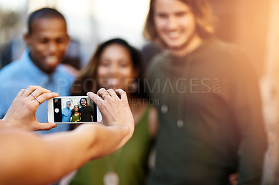 Buy stock photo Shot of a group of young friends having their picture taken on a smart phone