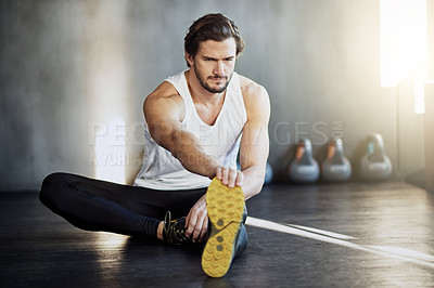 Buy stock photo Shot of a handsome young man warming up before his workout