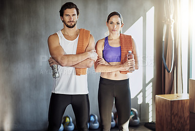 Buy stock photo Shot of two young people standing with their arms folded in the gym