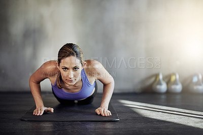 Buy stock photo Shot of an attractive young woman doing pushups as part of her workout