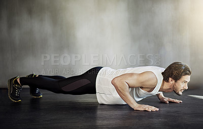 Buy stock photo Shot of a handsome young man doing pushups as part of his workout