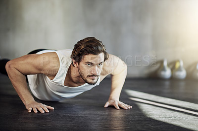 Buy stock photo Shot of a handsome young man doing pushups as part of his workout