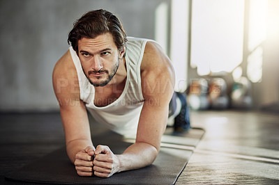 Buy stock photo Shot of a handsome young man planking as part of her workout