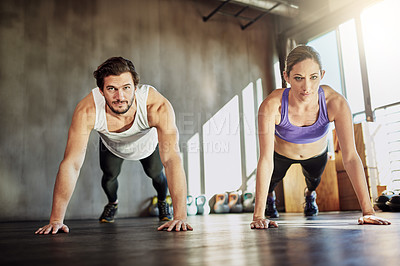 Buy stock photo Shot of two young people doing pushups as part of their workout