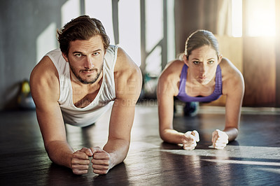 Buy stock photo Shot of two young people planking together as part of their workout