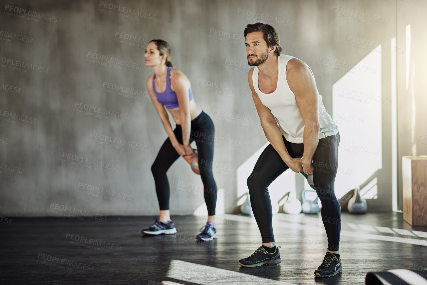 Buy stock photo Training, man and woman in gym with kettlebell, fitness and power at workout challenge together. Couple, sports club and personal trainer with weights, muscle development and healthy body exercise