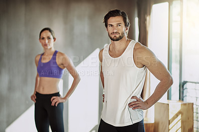 Buy stock photo Shot of two young people standing with their hands on their hips in the gym
