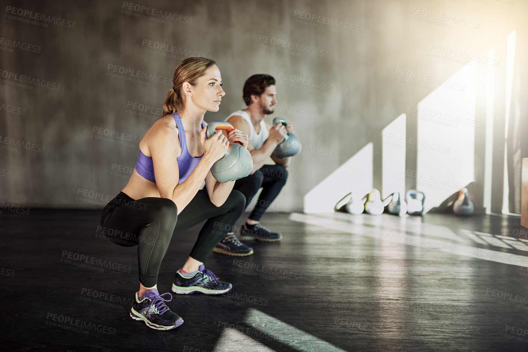 Buy stock photo Exercise, squat and couple in gym with kettlebell, power training and workout challenge together at sports club. Man, woman or personal trainer with muscle development, healthy body and fitness.