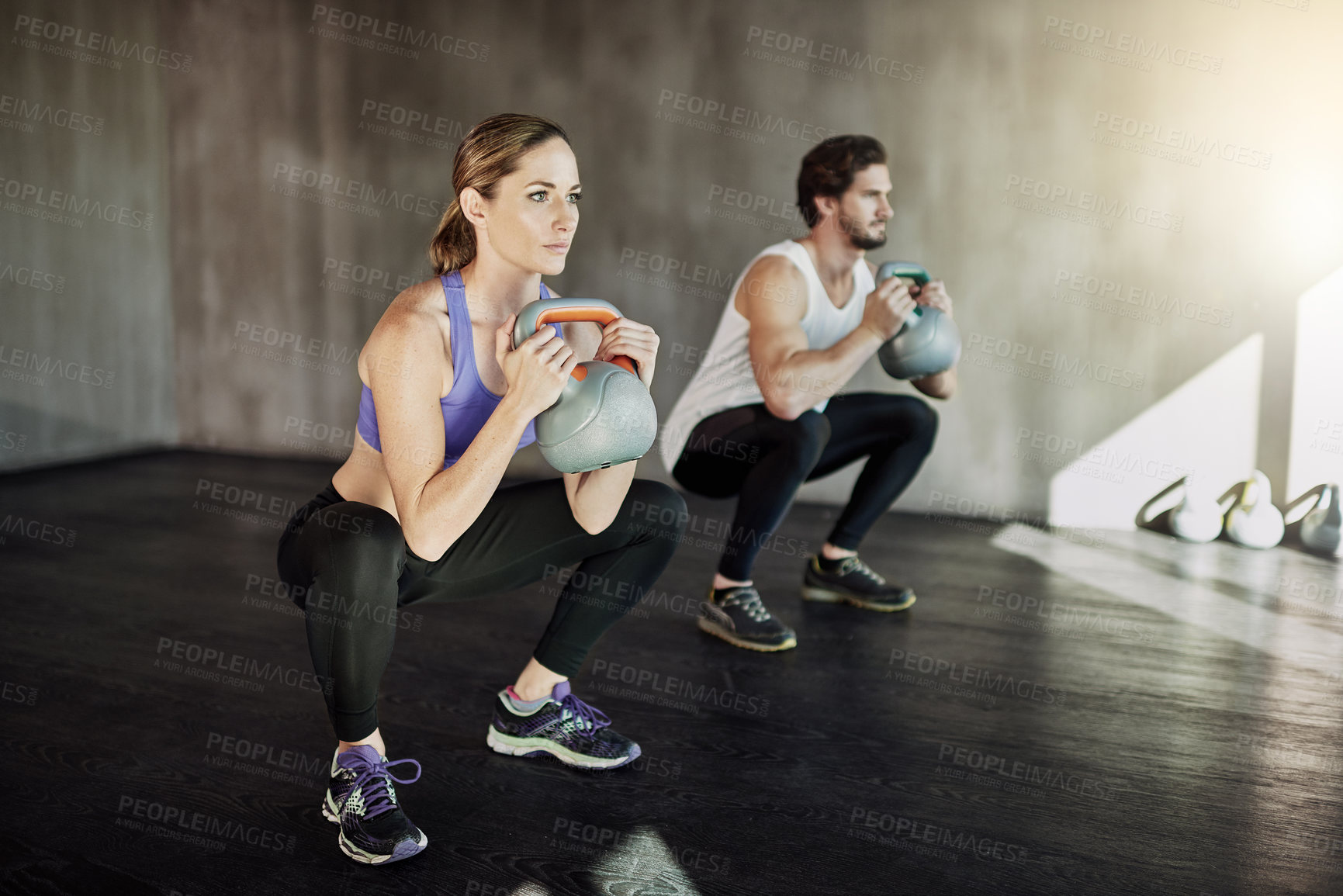 Buy stock photo Workout, squat and couple in gym with kettlebell, power training and fitness challenge together at sports club. Man, woman or personal trainer with muscle development, healthy body and exercise.