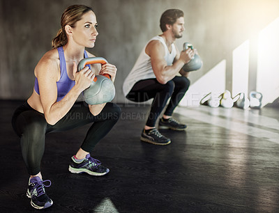 Buy stock photo Squat, man and woman in gym with kettlebell, fitness and power training at workout challenge together. Couple, sports club and personal trainer with weights, muscle development and body exercise.
