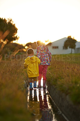 Buy stock photo Shot of a brother and sister splashing in water while playing together outside