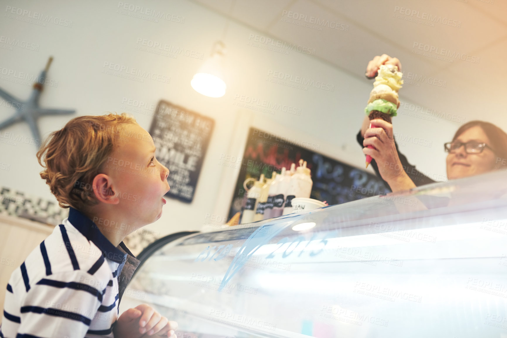 Buy stock photo Ice cream, happy and child in store for dessert with worker serving dessert for sweet treat. Excited, craving and server with scoop of frozen gelato in cone for boy kid customer in dairy shop.