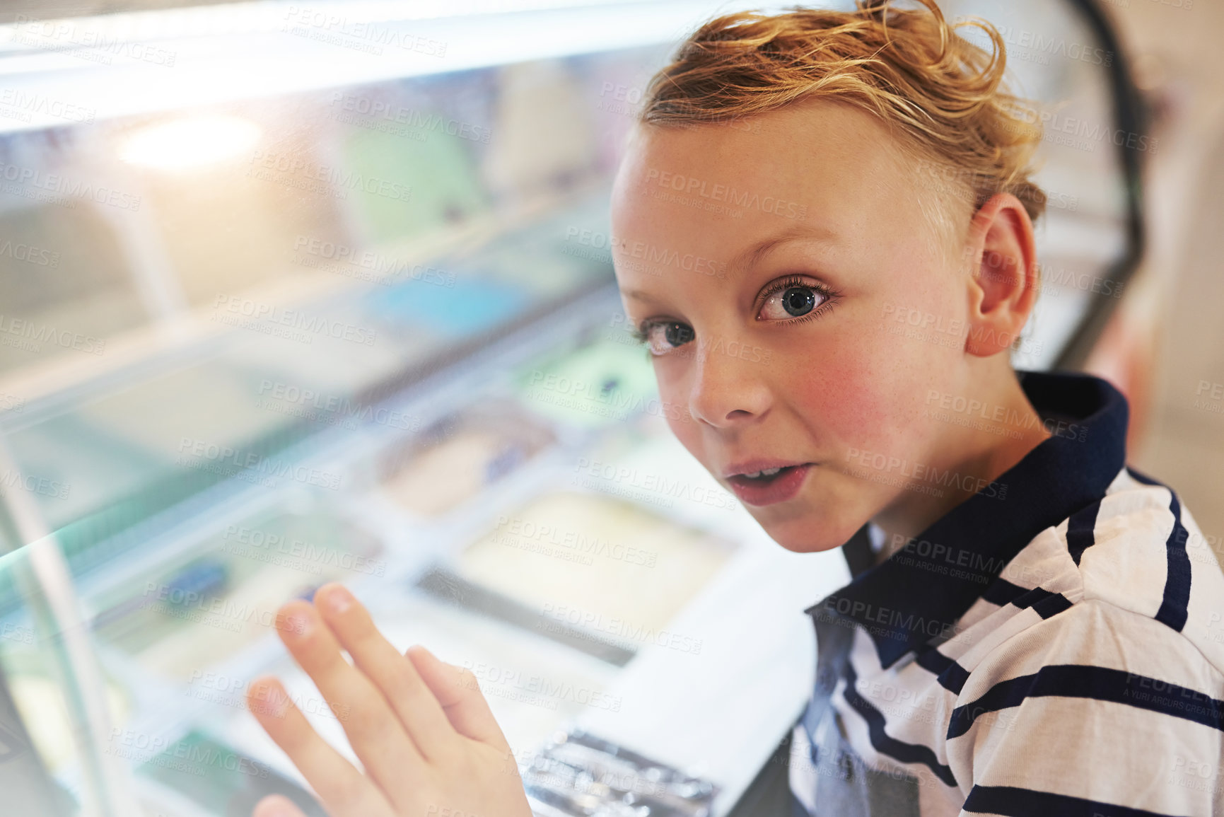 Buy stock photo Portrait of a young boy looking into a freezer at an ice cream store