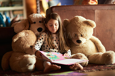 Buy stock photo Shot of a little girl reading a book with her teddy bears around her