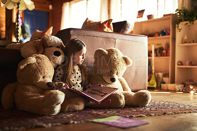 Buy stock photo Shot of a little girl reading a book with her teddy bears around her