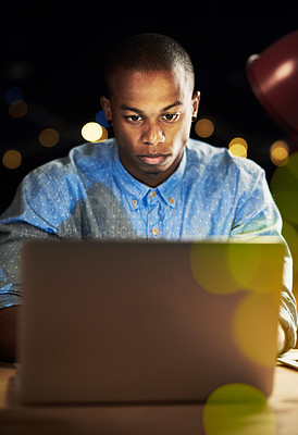 Buy stock photo Shot of a handsome young man working late night on his laptop